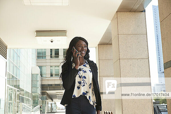 Businesswoman talking on mobile phone while standing at corridor