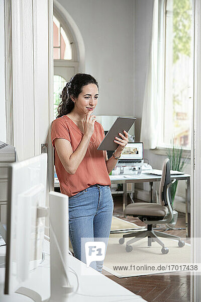 Geschäftsfrau verwendet digitales Tablet im Stehen im Büro