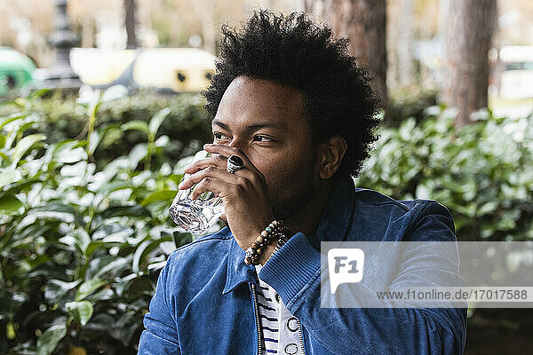 Close-up of mid adult man with afro hair drinking water at outdoor cafe
