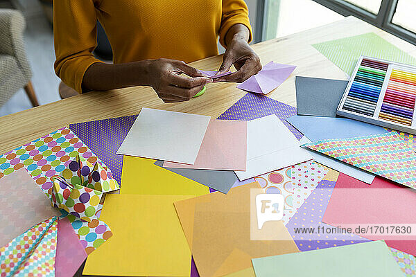 Origami-Künstlerin sitzt im Atelier und faltet buntes Papier