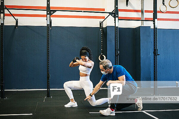 Männlicher Ausbilder trainiert eine Sportlerin im Fitnessstudio während COVID-19