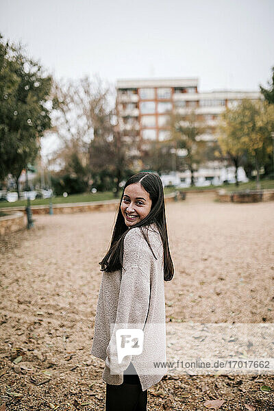 Smiling teenage girl posing while standing on land in park during winter