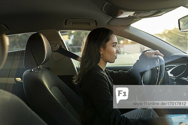 Junge Geschäftsfrau schaut beim Autofahren weg