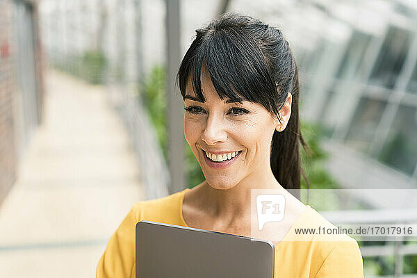 Businesswoman smiling with laptop in office