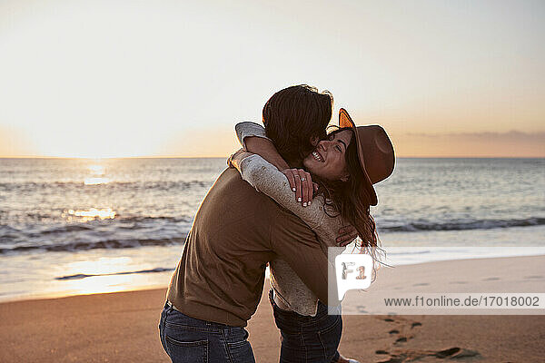 Junges Paar umarmt sich am Strand stehend
