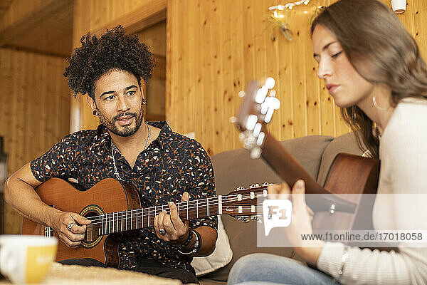Ehepaar probt zu Hause sitzend mit Gitarre