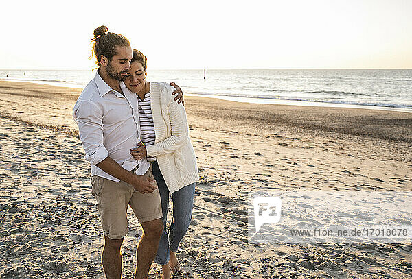 Romantisches junges Paar  das an einem sonnigen Tag am Strand spazieren geht
