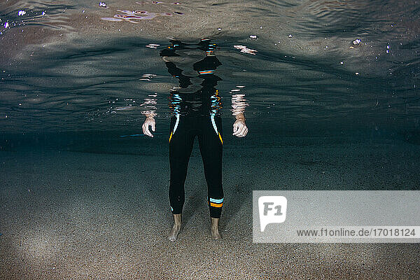 Unterwasseransicht eines niedrigen Ausschnitts eines Mannes auf sandigem Meeresboden