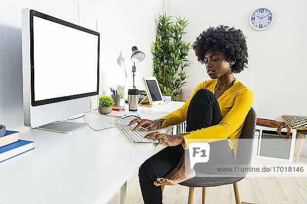 Woman working on computer while sitting on chair at home