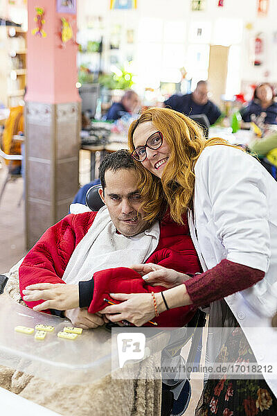 Smiling female caregiver with disabled man in nursing home