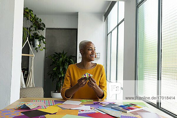 Origami-Künstlerin sitzt im Atelier und arbeitet mit buntem Papier