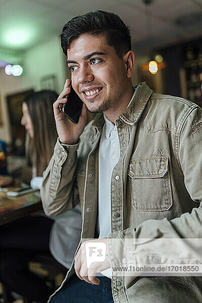 Junger Mann spricht im Restaurant mit seinem Smartphone