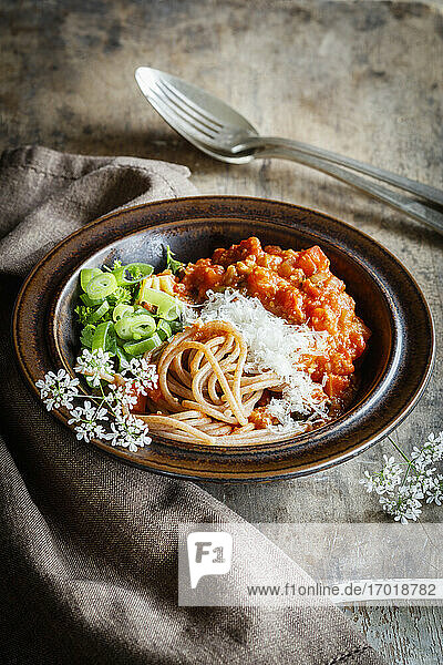 Teller mit vegetarischer Spaghetti Bolognese mit Wildblumen  Frühlingszwiebeln und Grunkern aus Dinkel