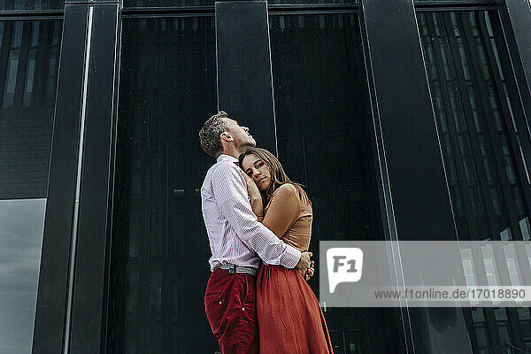Zärtliches heterosexuelles Paar  das sich an einem Gebäude umarmt