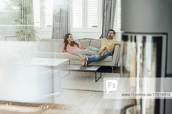 Reifes Paar entspannt sich auf dem Sofa und unterhält sich im Wohnzimmer