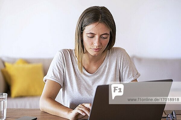 Schöne Frau  die einen Laptop bei der Arbeit zu Hause benutzt