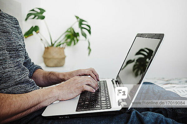Mann arbeitet zu Hause sitzend am Laptop
