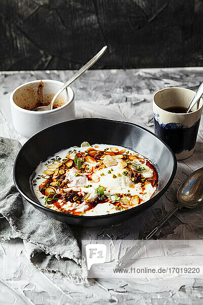 Frühstück mit pochierten Eiern  Joghurt und würziger Paprikabutter in einer Schüssel auf dem Tisch