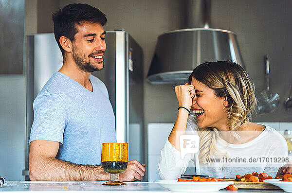 Laughing young woman with boyfriend in kitchen at home