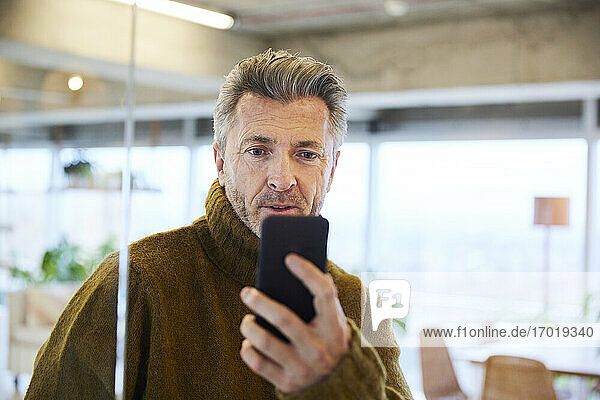 Surprised man looking at mobile phone at home
