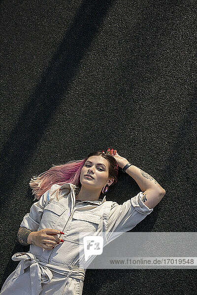Young woman with blank expression lying on back at sports court