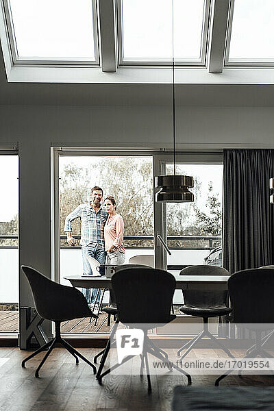 Mature couple standing in balcony at apartment