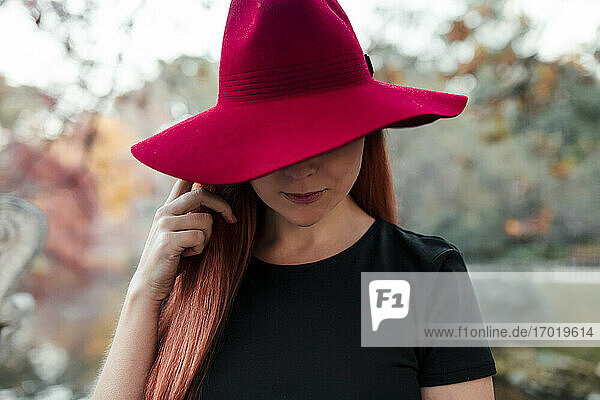 Nahaufnahme einer mittleren erwachsenen Frau mit rotem Hut im Park
