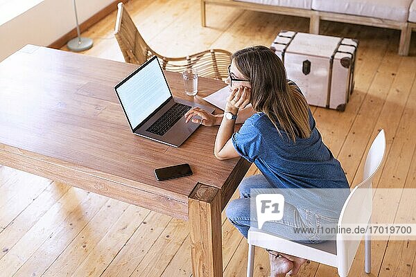 Nachdenkliche brünette Unternehmerin mit Laptop im Home Office