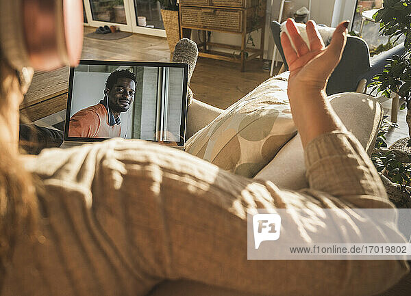 Junger Mann lächelt während eines Videogesprächs mit einer Frau auf dem Laptop-Bildschirm