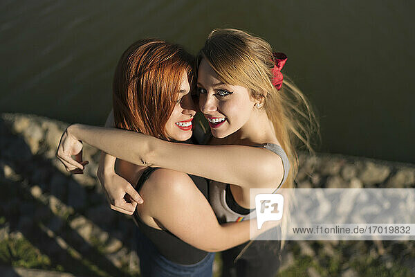 Lächelndes lesbisches Paar  das sich umarmt  während es am See steht