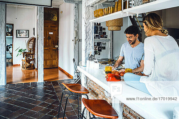 Junger Mann bereitet mit Freundin in der Küche zu Hause Essen zu