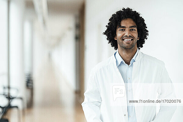 Lächelnder junger Arzt auf dem Krankenhausflur