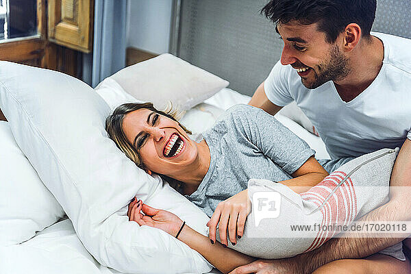 Lachendes junges Paar  das zu Hause im Bett liegt