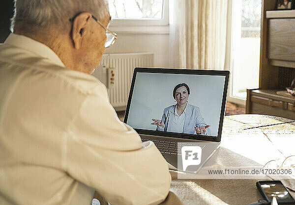 Eine Ärztin berät einen älteren männlichen Patienten während eines Videoanrufs zu Hause