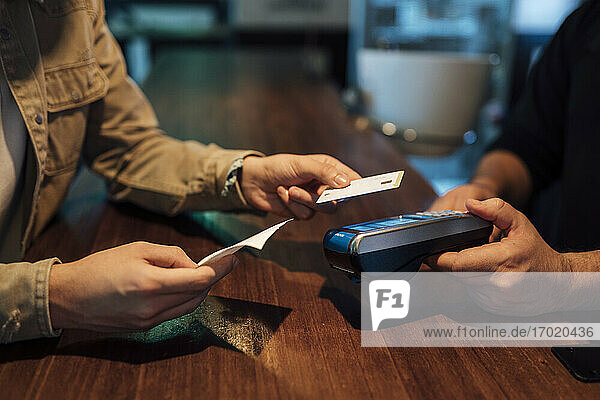 Männerhände beim Bezahlen mit Kreditkarte im Restaurant