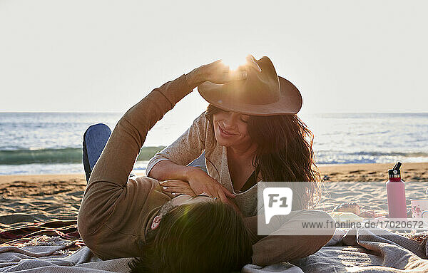 Verspieltes junges Paar ruht sich am Strand aus