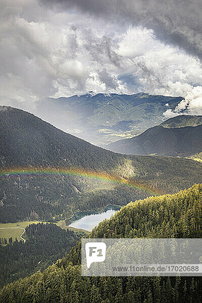 Regenbogen über Berglandschaft mit See