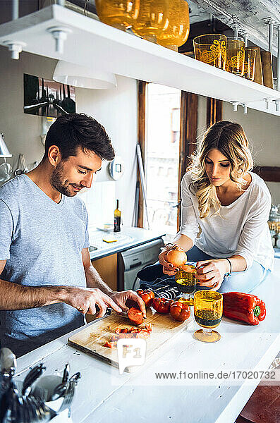 Young man preparing food with girlfriend in kitchen at home