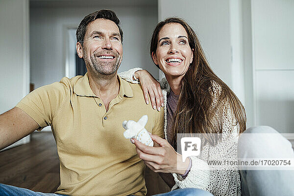 Happy couple with stuffed elephant toy looking away at home