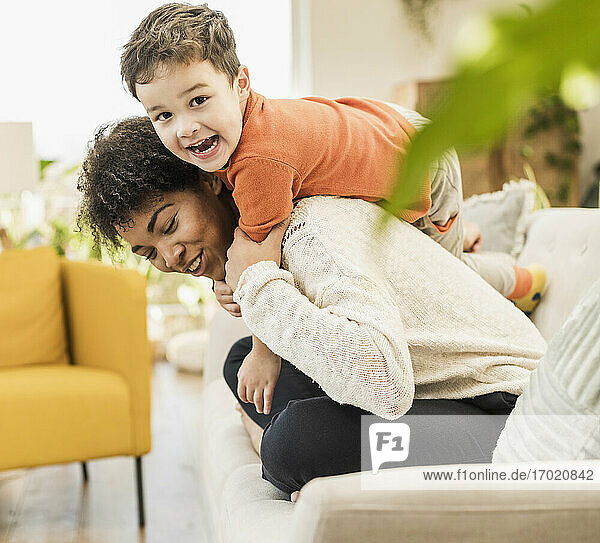 Fröhliche Mutter und Sohn spielen zu Hause auf dem Sofa sitzend