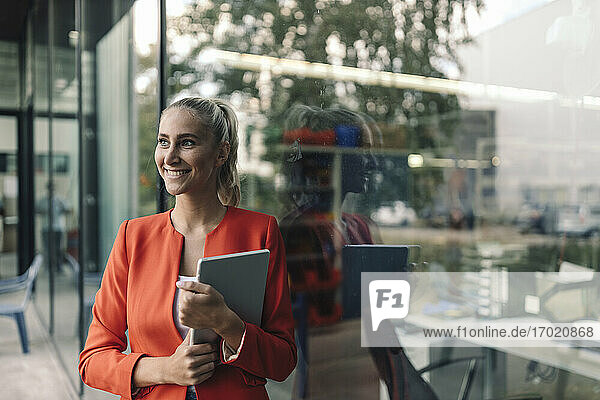 Glückliche Unternehmerin mit digitalem Tablet vor dem Büro