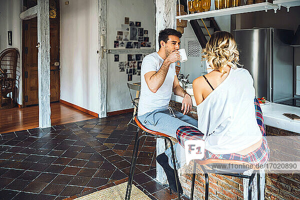 Young couple sitting at kitchen counter and having breakfast