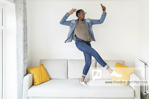Frau tanzt auf Sofa