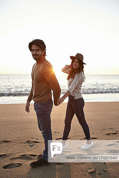 Young couple holding hands while walking on beach