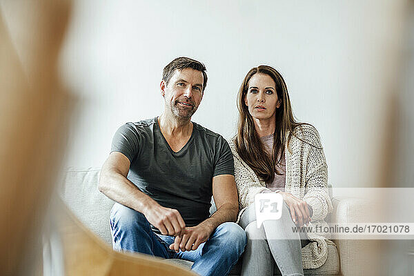 Selbstbewusstes reifes Paar vor weißer Wand in Wohnung