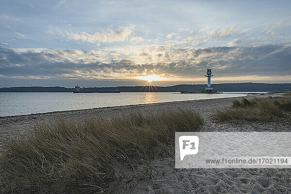 Deutschland  Schleswig-Holstein  Friedrichsort  Sandstrand bei Sonnenaufgang mit Leuchtturm im Hintergrund