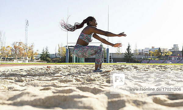 Weibliche Sportlerin balanciert auf Sand gegen den klaren Himmel an einem sonnigen Tag