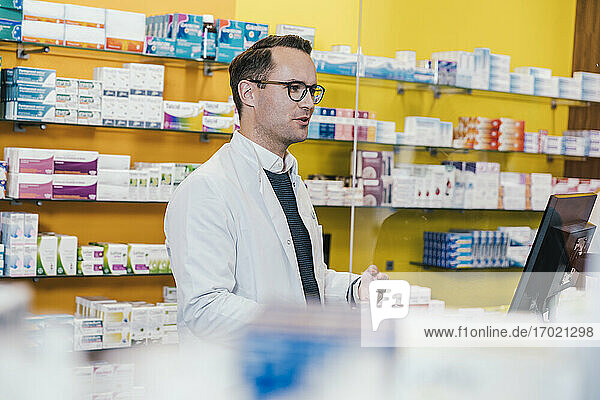 Pharmacist wearing lab coat while working in chemist shop