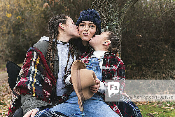 Zwei Mädchen küssen ihre Schwester in einer Herbstlandschaft