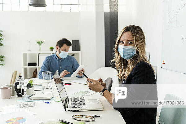 Business people wearing protective masks working in office 